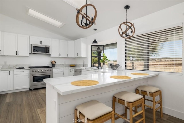 kitchen featuring white cabinets, lofted ceiling, stainless steel appliances, and hanging light fixtures