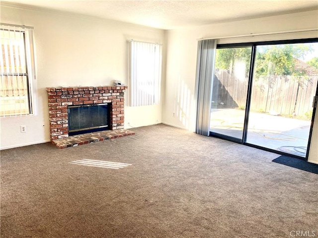 unfurnished living room featuring carpet floors, ornamental molding, a textured ceiling, and a brick fireplace