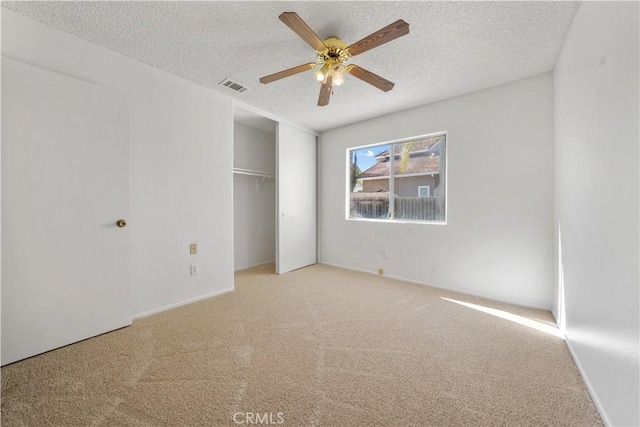 unfurnished bedroom with ceiling fan, light carpet, and a textured ceiling