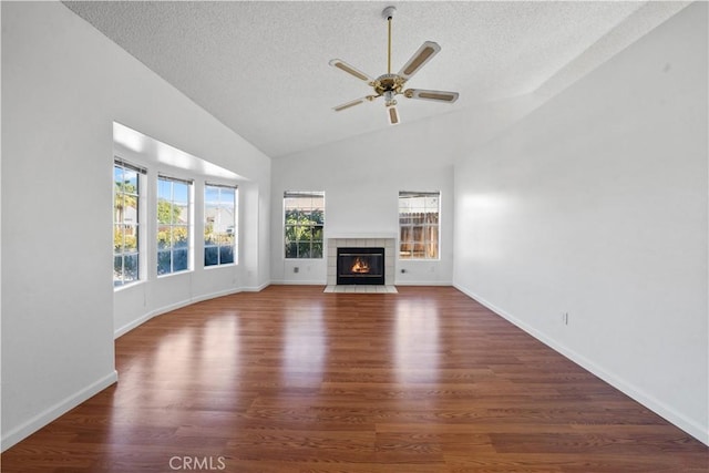 unfurnished living room featuring a tile fireplace, ceiling fan, dark hardwood / wood-style flooring, and a textured ceiling