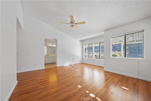 spare room featuring a textured ceiling, hardwood / wood-style flooring, vaulted ceiling, and ceiling fan