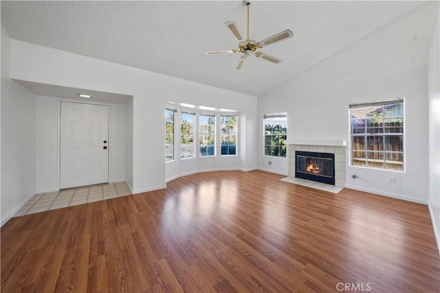 unfurnished living room featuring a fireplace, ceiling fan, light hardwood / wood-style flooring, and a healthy amount of sunlight