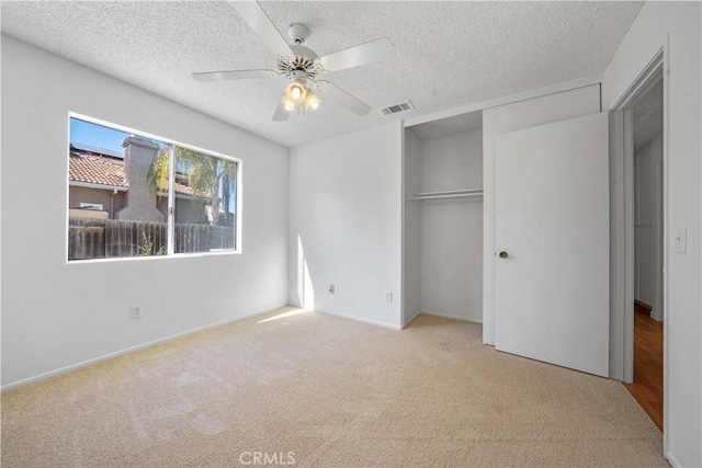 unfurnished bedroom with light carpet, a textured ceiling, a closet, and ceiling fan