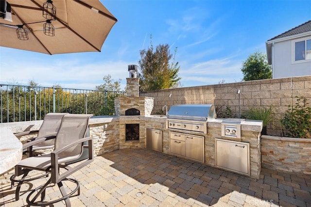 view of patio / terrace featuring an outdoor stone fireplace, area for grilling, and grilling area