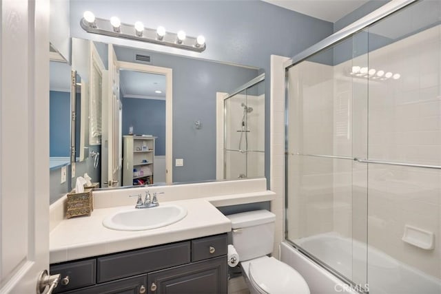 full bathroom with shower / bath combination with glass door, toilet, vanity, and ornamental molding