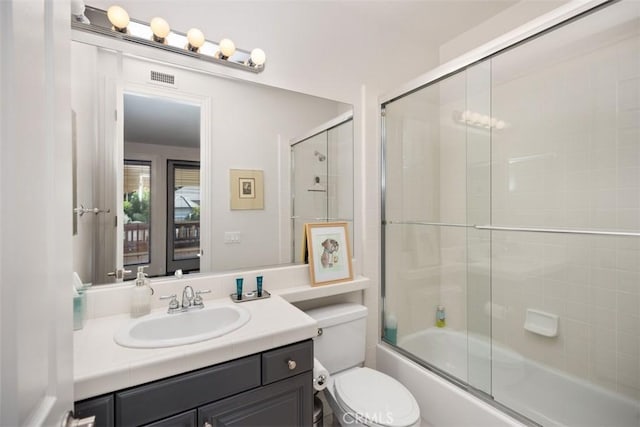 full bathroom with vanity, toilet, and bath / shower combo with glass door