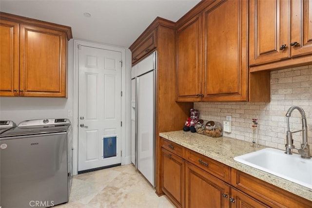 kitchen with backsplash, sink, white built in fridge, light stone countertops, and independent washer and dryer