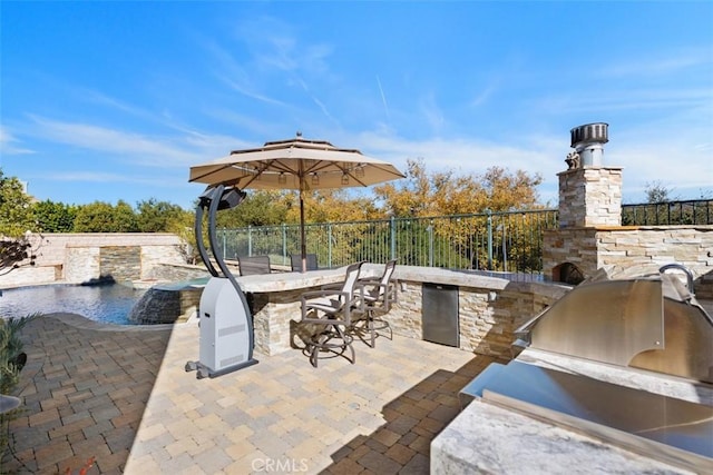 view of patio with pool water feature, an outdoor kitchen, a grill, and an outdoor bar