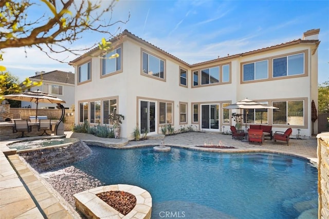 back of house with a pool with hot tub, a patio area, and an outdoor fire pit