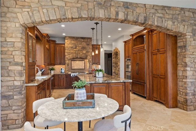 kitchen featuring decorative backsplash, appliances with stainless steel finishes, light stone counters, pendant lighting, and a kitchen island