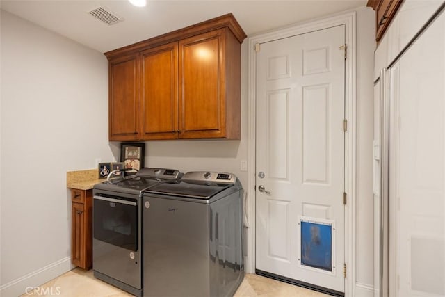 washroom featuring cabinets and washer and clothes dryer