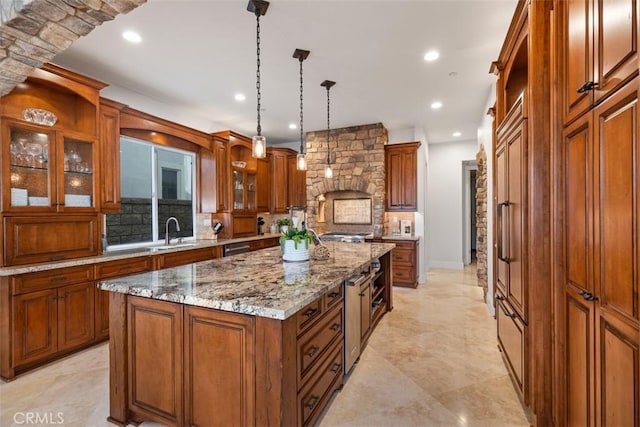 kitchen featuring light stone countertops, backsplash, sink, pendant lighting, and a center island