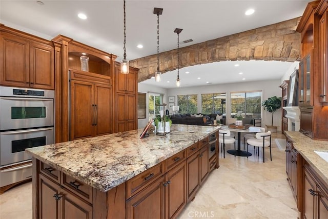 kitchen with light stone countertops, a center island, paneled fridge, double oven, and decorative light fixtures