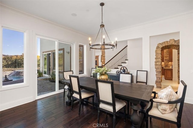 dining area with dark hardwood / wood-style floors, crown molding, and a notable chandelier