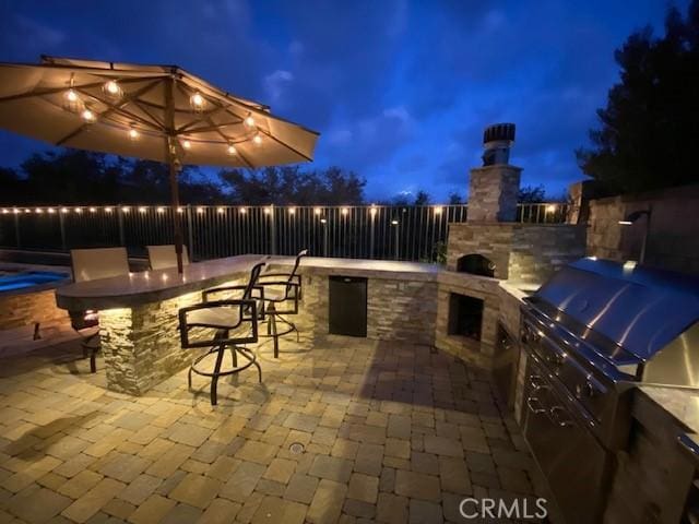 patio at twilight featuring exterior bar and exterior kitchen