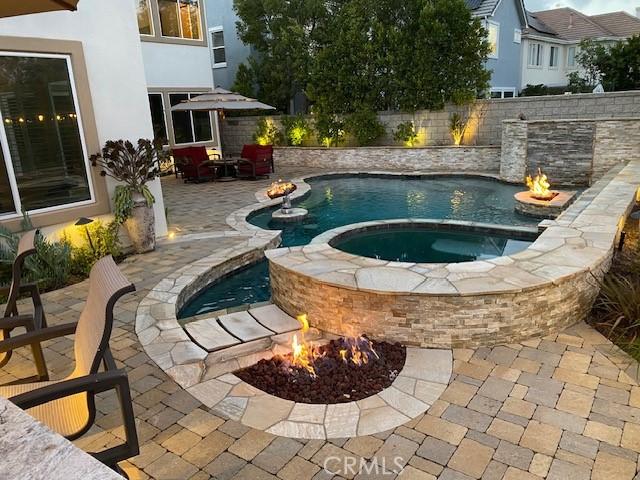 view of pool featuring a patio area, an in ground hot tub, and a fire pit