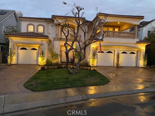 mediterranean / spanish-style house featuring a garage, a balcony, and a front yard