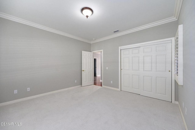 unfurnished bedroom featuring light colored carpet, ornamental molding, and a closet