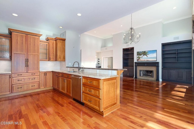 kitchen with kitchen peninsula, built in shelves, sink, dishwasher, and hardwood / wood-style floors