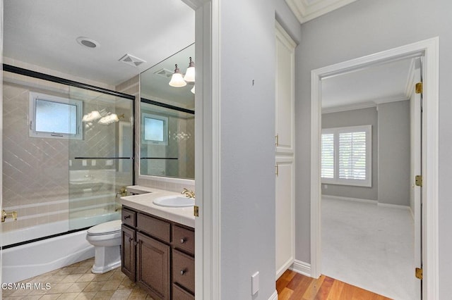 full bathroom with vanity, shower / bath combination with glass door, crown molding, hardwood / wood-style flooring, and toilet