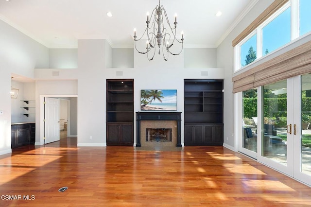 unfurnished living room with french doors, a towering ceiling, hardwood / wood-style flooring, and ornamental molding