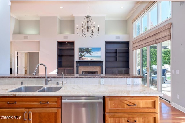 kitchen featuring dishwasher, sink, light hardwood / wood-style flooring, light stone countertops, and a chandelier