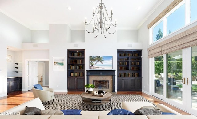 living room with french doors, a high ceiling, built in features, wood-type flooring, and ornamental molding