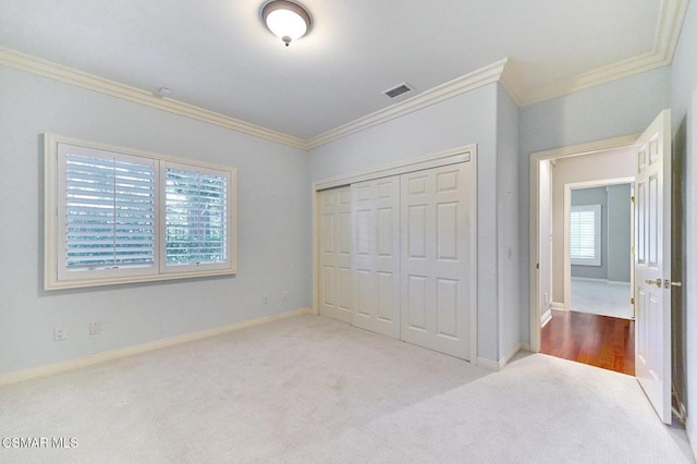 unfurnished bedroom featuring a closet, crown molding, light carpet, and multiple windows