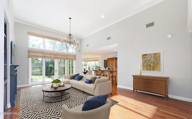 living room featuring plenty of natural light, a towering ceiling, hardwood / wood-style floors, and ornamental molding