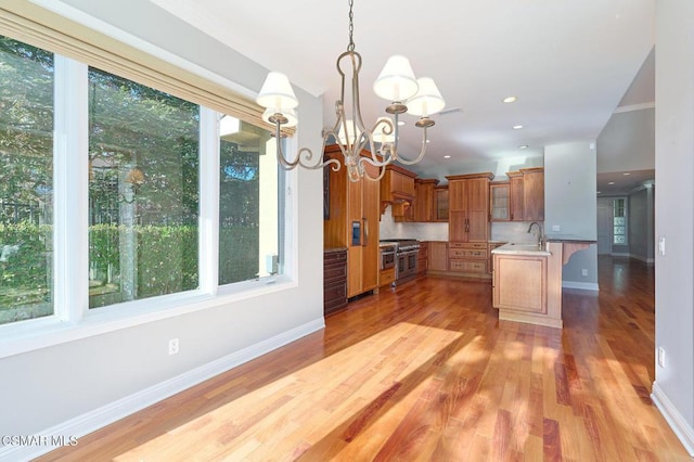 kitchen featuring light wood-type flooring, crown molding, pendant lighting, double oven range, and a chandelier