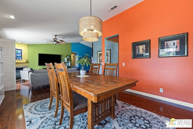 dining room featuring vaulted ceiling, dark hardwood / wood-style flooring, and ceiling fan with notable chandelier