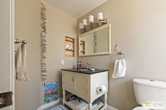 bathroom featuring vanity, a textured ceiling, and toilet