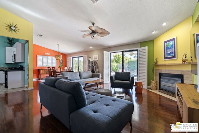 living room with a textured ceiling, ceiling fan, dark wood-type flooring, and vaulted ceiling