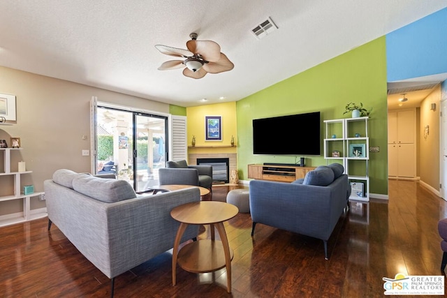 living room featuring ceiling fan, dark hardwood / wood-style flooring, lofted ceiling, and a textured ceiling