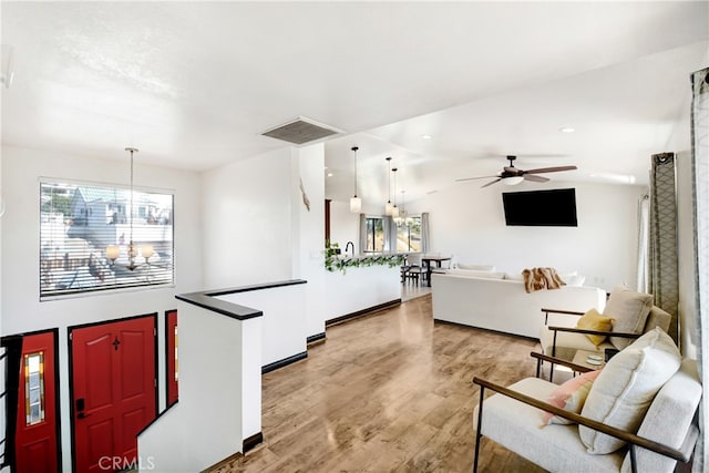 kitchen featuring vaulted ceiling, hardwood / wood-style flooring, decorative light fixtures, and ceiling fan with notable chandelier