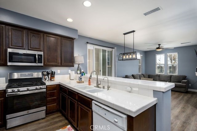 kitchen featuring ceiling fan, sink, dark hardwood / wood-style floors, kitchen peninsula, and appliances with stainless steel finishes