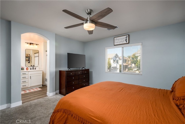 carpeted bedroom with ensuite bath, ceiling fan, and sink