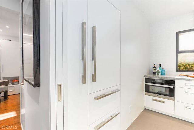 kitchen featuring white cabinets, oven, and light hardwood / wood-style floors