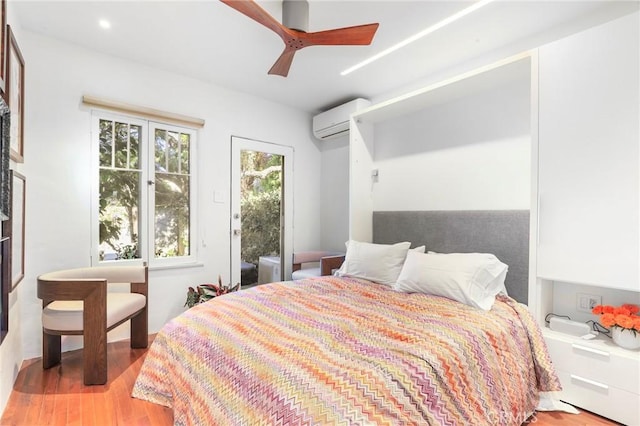 bedroom featuring access to outside, light hardwood / wood-style flooring, an AC wall unit, and ceiling fan