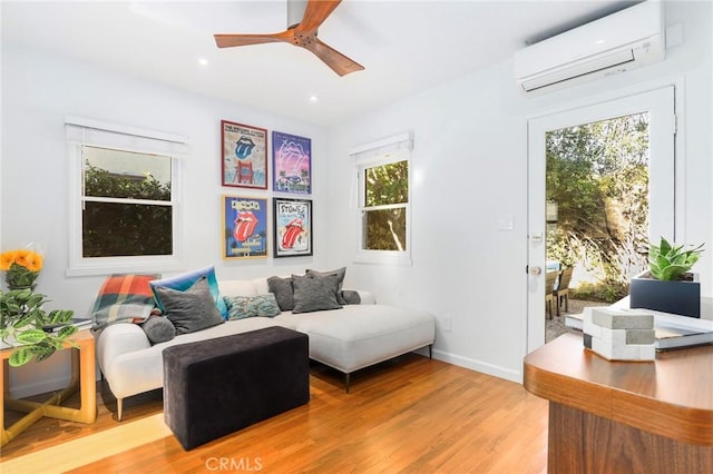 living room featuring ceiling fan, a healthy amount of sunlight, a wall unit AC, and light hardwood / wood-style flooring