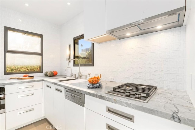 kitchen featuring range hood, white cabinetry, stainless steel gas stovetop, and sink