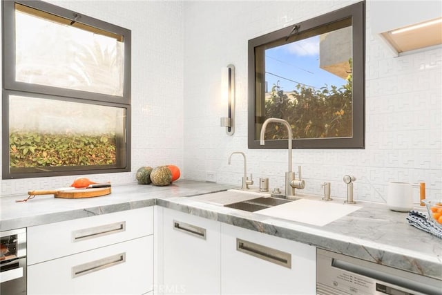 kitchen featuring white cabinets, decorative backsplash, dishwasher, and sink