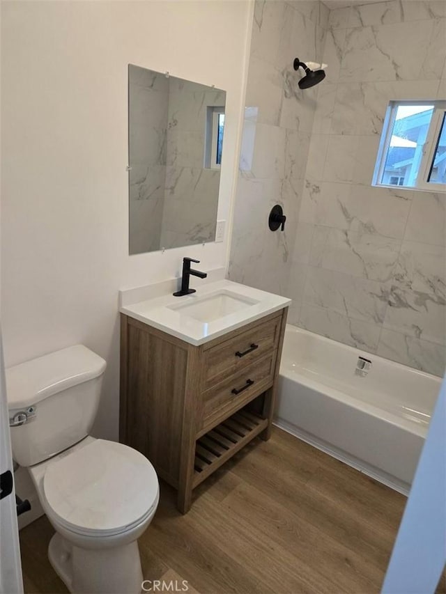 full bathroom with vanity, hardwood / wood-style flooring, toilet, and tiled shower / bath