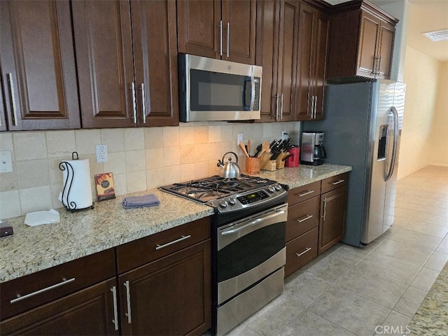 kitchen with decorative backsplash, light stone counters, and appliances with stainless steel finishes