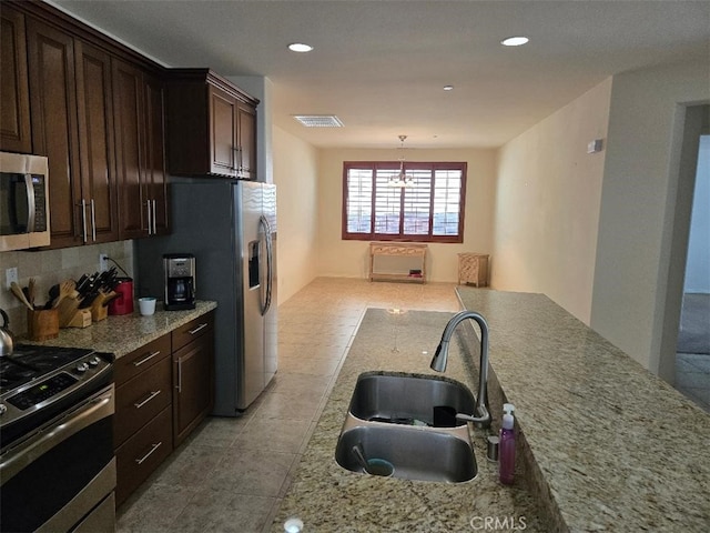 kitchen with hanging light fixtures, sink, appliances with stainless steel finishes, a notable chandelier, and dark brown cabinets