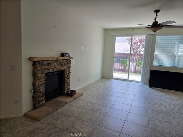 unfurnished living room featuring light tile patterned floors, a stone fireplace, and ceiling fan