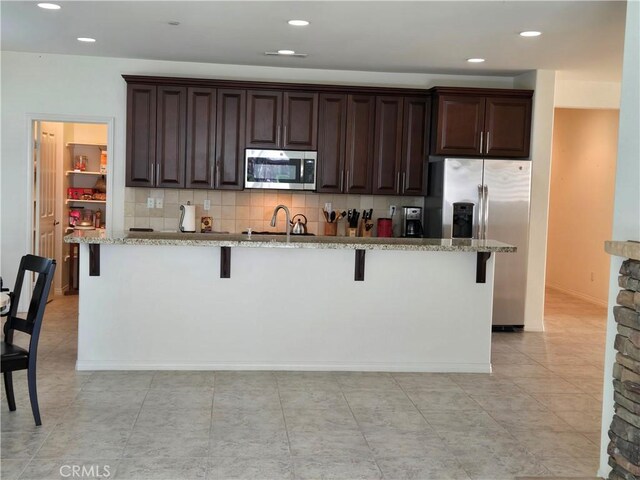 kitchen featuring a breakfast bar, stainless steel appliances, a center island with sink, and sink