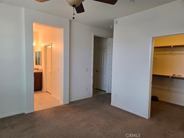 unfurnished bedroom featuring light carpet, a closet, a spacious closet, and ceiling fan