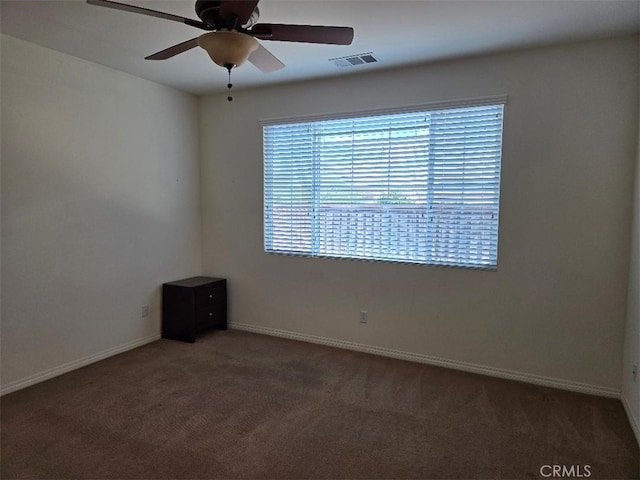 unfurnished room with dark colored carpet and ceiling fan