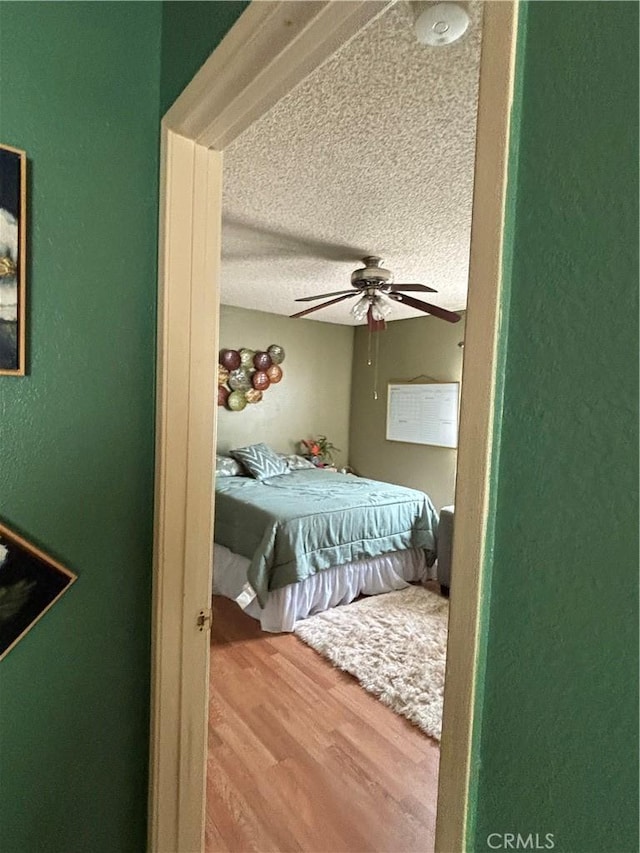 bedroom featuring hardwood / wood-style flooring, ceiling fan, and a textured ceiling